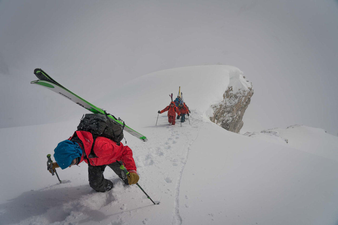 Steep ski hill perspective of two backcountry skiers climbing with gear on their backs